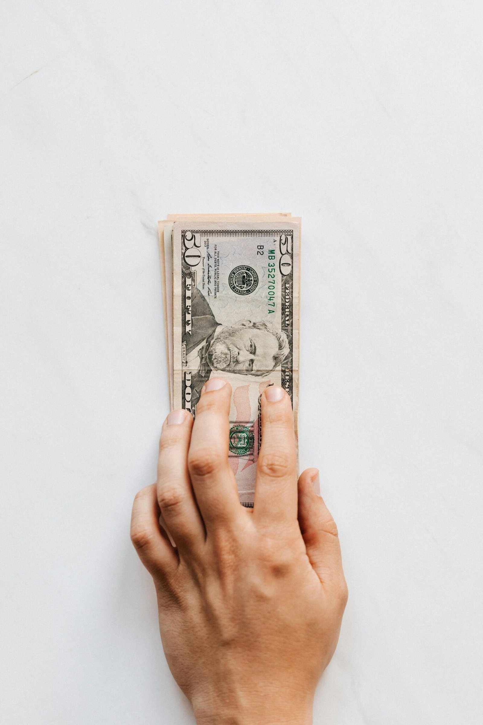 A hand holds a stack of US dollar bills, symbolizing wealth and finance.